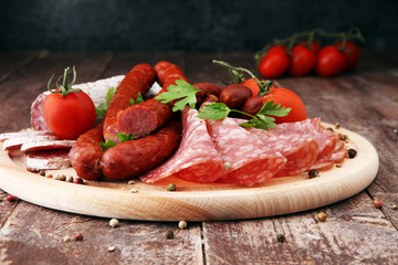 Food tray with delicious salami, pieces of sliced ham, sausage, tomatoes, salad and vegetable - Meat platter with selection - Cutting sausage and cured meat