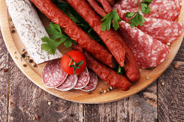 Food tray with delicious salami, pieces of sliced ham, sausage, tomatoes, salad and vegetable - Meat platter with selection - Cutting sausage and cured meat