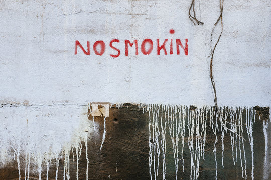 "NO SMOKING" sign painted on old building wall