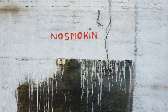 "NO SMOKING" sign painted on old building wall