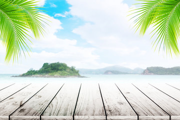 Empty wooden table and coconut leaves with party on beach blurred background in summer time.