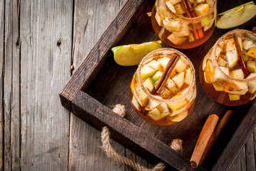 Autumn and winter drinks. Warm apple sangria, apple cider with pieces of fruit, cinnamon, spices,...