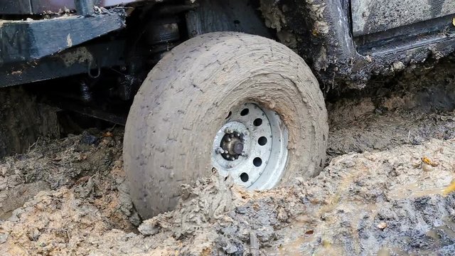 SUV 4WD car stuck in muddy off-road. Closeup the wheel rotates in the mud.