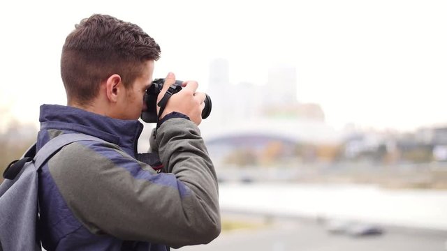 Young handsome man takes photo of the camera with own camera and smiles