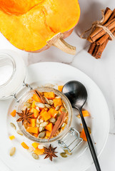Healthy vegan food. Dietary breakfast or snack. Pumpkin pie overnight oats, with  pumpkin, yogurt, cinnamon, spices. In a glass, on a white marble table. Copy space top view