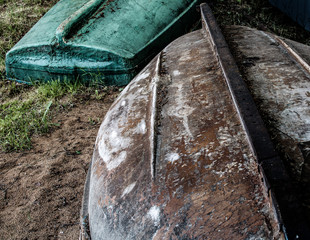 Two upturned boats lie on the shore. The boat is made of plastic.
