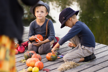 Glad children paint small Halloween pumpkins