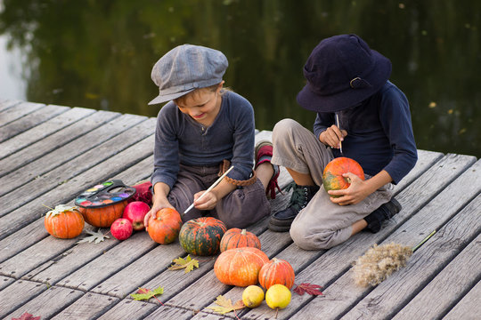 Cheerful children paint small Halloween pumpkins