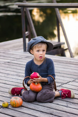 Fototapeta premium Ordinary boy sitting with pumpkins and apples