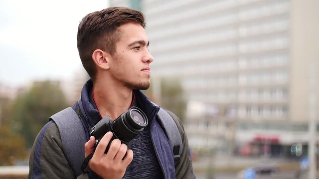 Young handsome man takes photo of the camera with own camera and smiles