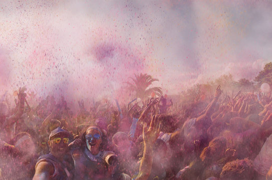 A crazy couple taking a selfie at a concert where holi powder is flying in the air