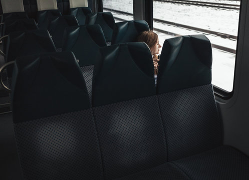 Young traveling woman listening to the music using headphones looking through train window