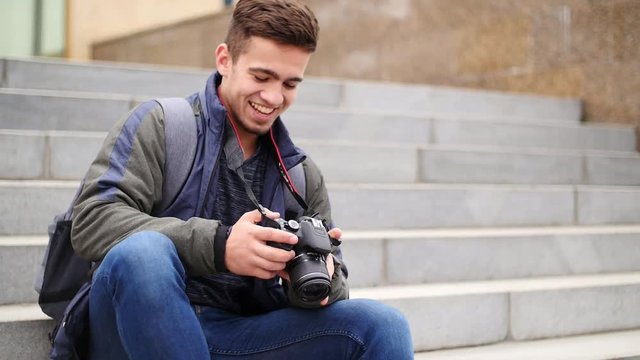 Young guy looks at the digital camera while in the city