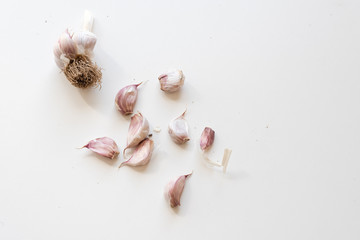 High angle view of unpeeled garlic cloves on white table with copy space (selective focus)