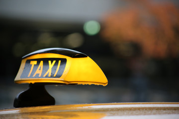 Taxi sign on taxi car with blurred city background, selective focus copy with space