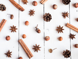 Cinnamon sticks spice star fir cones on white wooden background Flat lay