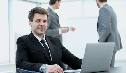 successful businessman sitting at the table with an open laptop 