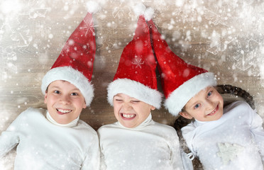 happy child lying together in a row on wooden background, dressed in christmas Santa hat and having fun, winter holiday concept, snow decoration