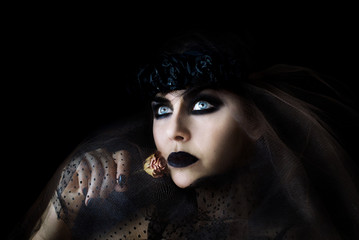 darkhair gothic girl with black lips and dry rose in her hand