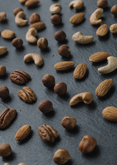 Variety of mixed nuts - almond, hazelnuts and cashew - on the dark slate background with copy space. Top view. Toned