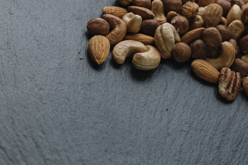 Variety of mixed nuts - almond, hazelnuts and cashew - on the dark slate background with copy space. Top view. Toned