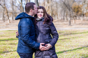 Fototapeta premium Beautiful pregnant woman and her handsome husband hugging the tummy