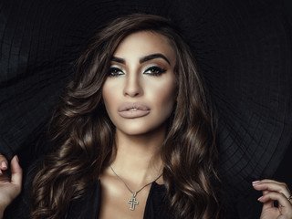 Close up portrait of a gorgeous woman with luxuriant shining wavy hair and perfect make up holding...