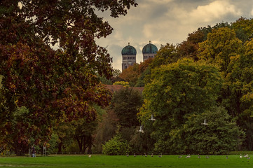 Fototapeta na wymiar Herbst in München, bunte Blätter im Englischen Garten, Ausflug in die Natur die Frauenkirche im Blick