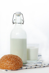 Glass bottle with milk glass Cup and bread on a napkin on white 