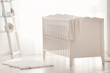 Beautiful light room with crib and toys on shelves