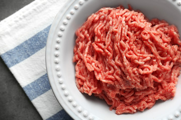 Plate with fresh raw minced meat on table
