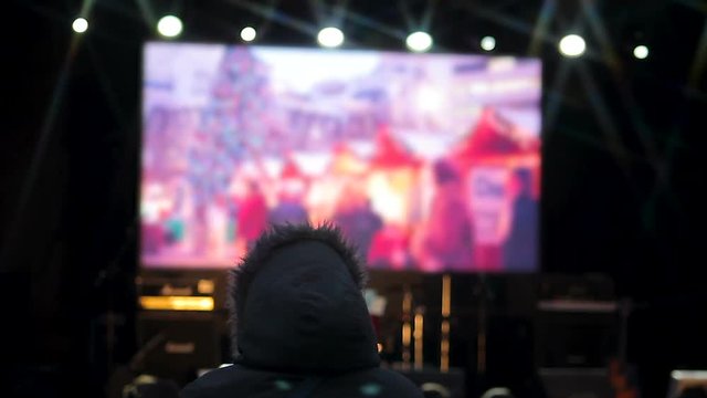 People watching clips of upcoming celebration on big screen in central square