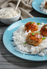 Plate with delicious meatballs and rice on wooden table