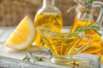 Gravy boat with rosemary oil on wooden board