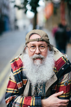 Man with white hair and beard wearing cap backwards