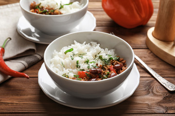 Chili con carne served with rice in bowl on wooden table