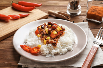 Chili con carne served with rice on wooden table