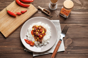Chili con carne served with rice on wooden table