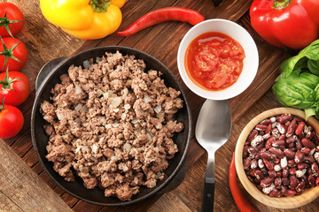 Cooked minced meat, sauce and vegetables on kitchen table