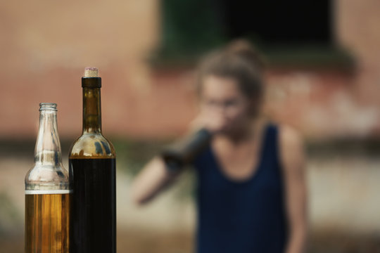 Bottles with alcohol on blurred view of drunk woman