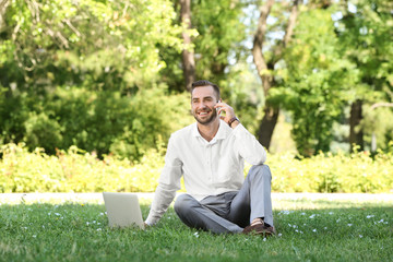 Naklejka na ściany i meble Elegant man with laptop talking on phone in park