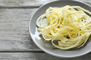 Plate with courgette spaghetti on wooden table