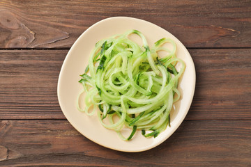 Plate with raw vegetable spaghetti on wooden table