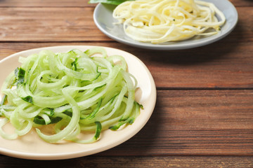 Plate with raw vegetable spaghetti on wooden table