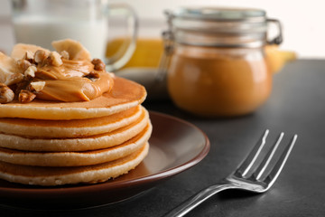 Plate with yummy banana pancakes on table