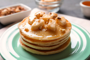 Plate with yummy banana pancakes on table