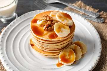 Plate with yummy banana pancakes on table
