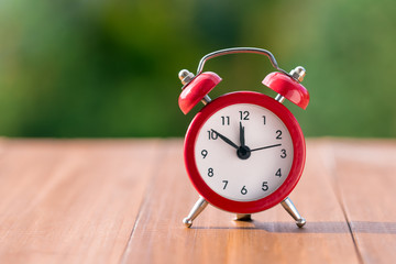 Red vintage clock on natural background. Autumn time change