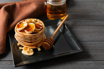 Plate with yummy banana pancakes on wooden table