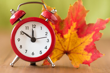 Red vintage clock and mable leaf. Autumn time change